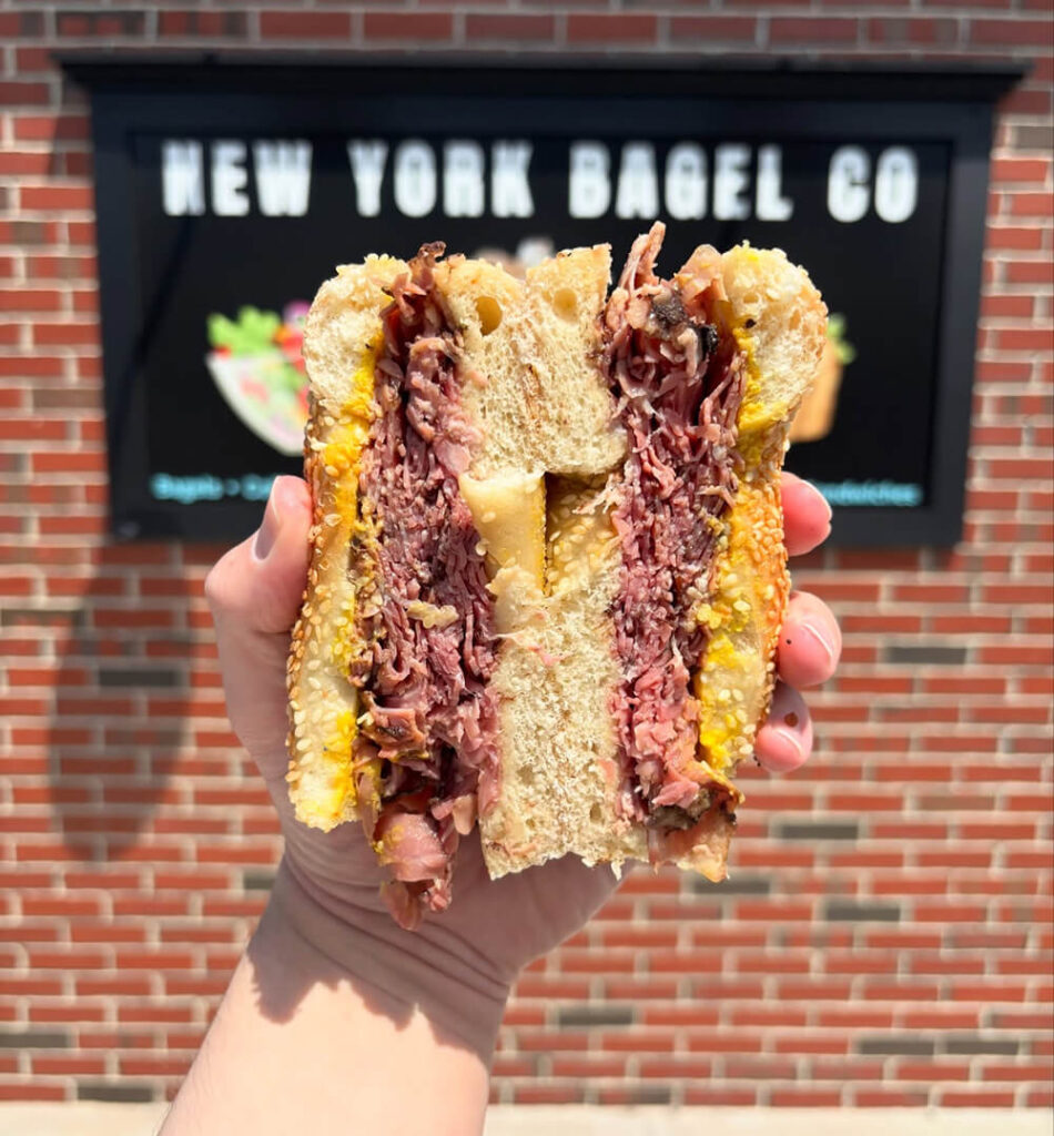 Pastrami sandwich in front of an NYBC storefront